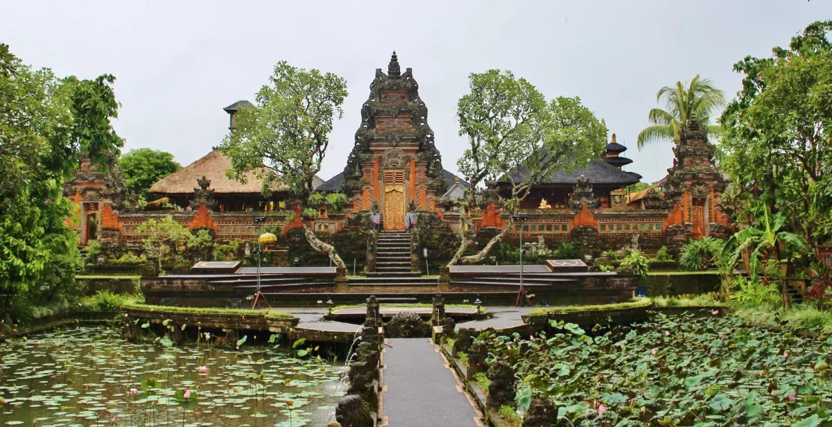 Ein Tempel auf Bali in Ubud. Ein Steg mit links und rechts einem Teich mit Seerosen. Dahinter die Tempelanlage.